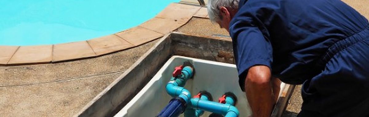 Técnico revisando la bomba y el filtro de la depuradora de una piscina